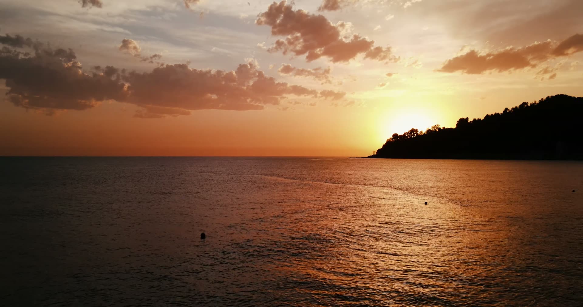 Golden sunset over the ocean behind a coastal headland